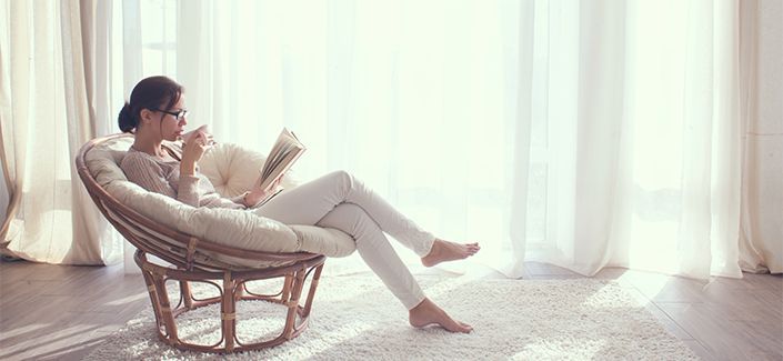 Young woman at home sitting on modern chair in front of window r