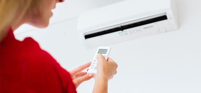 Woman using air-condition with remote control
